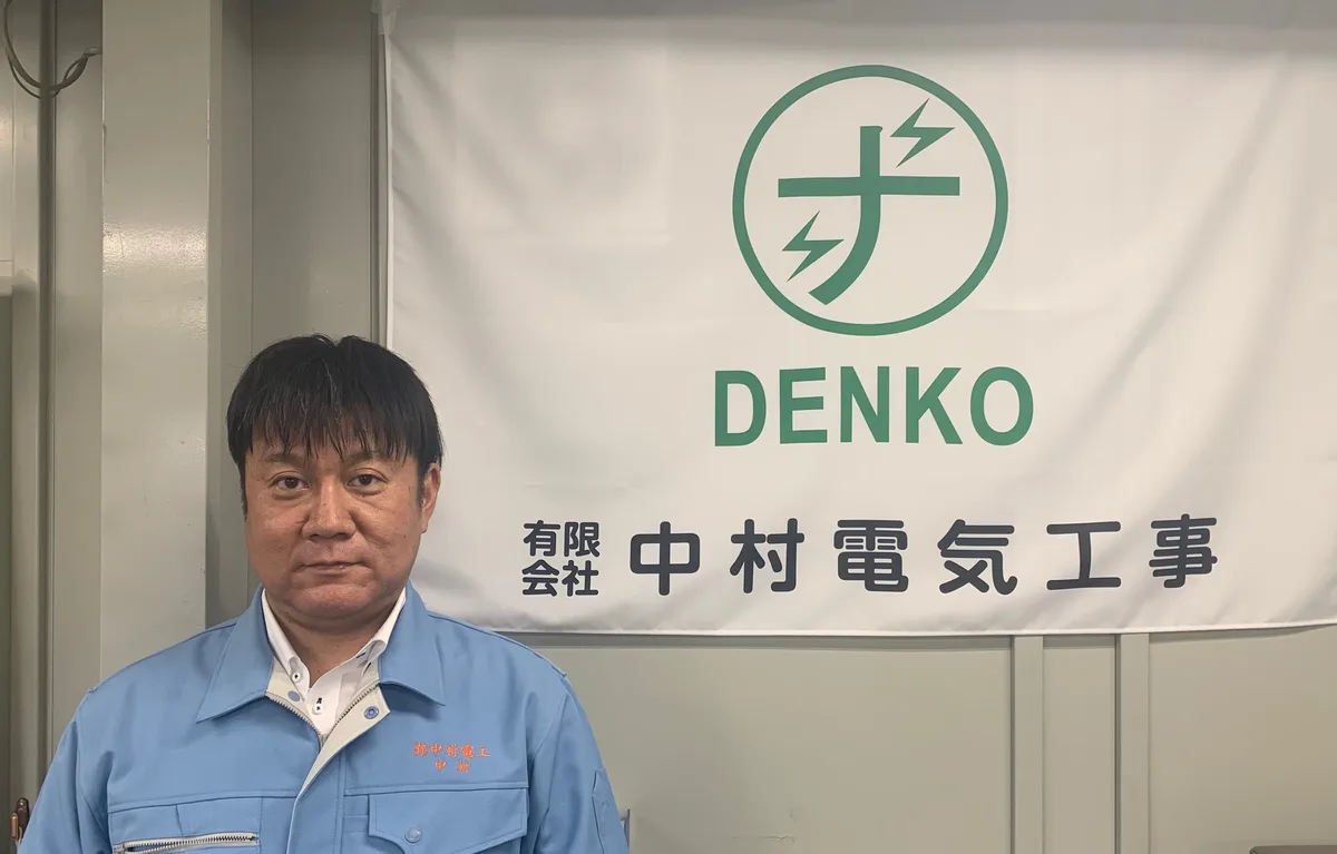 社名の幕の前に立つ代表者