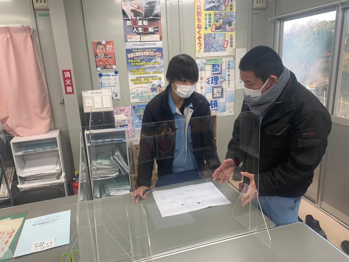 図面を確認しながら打ち合わせる2人の作業員